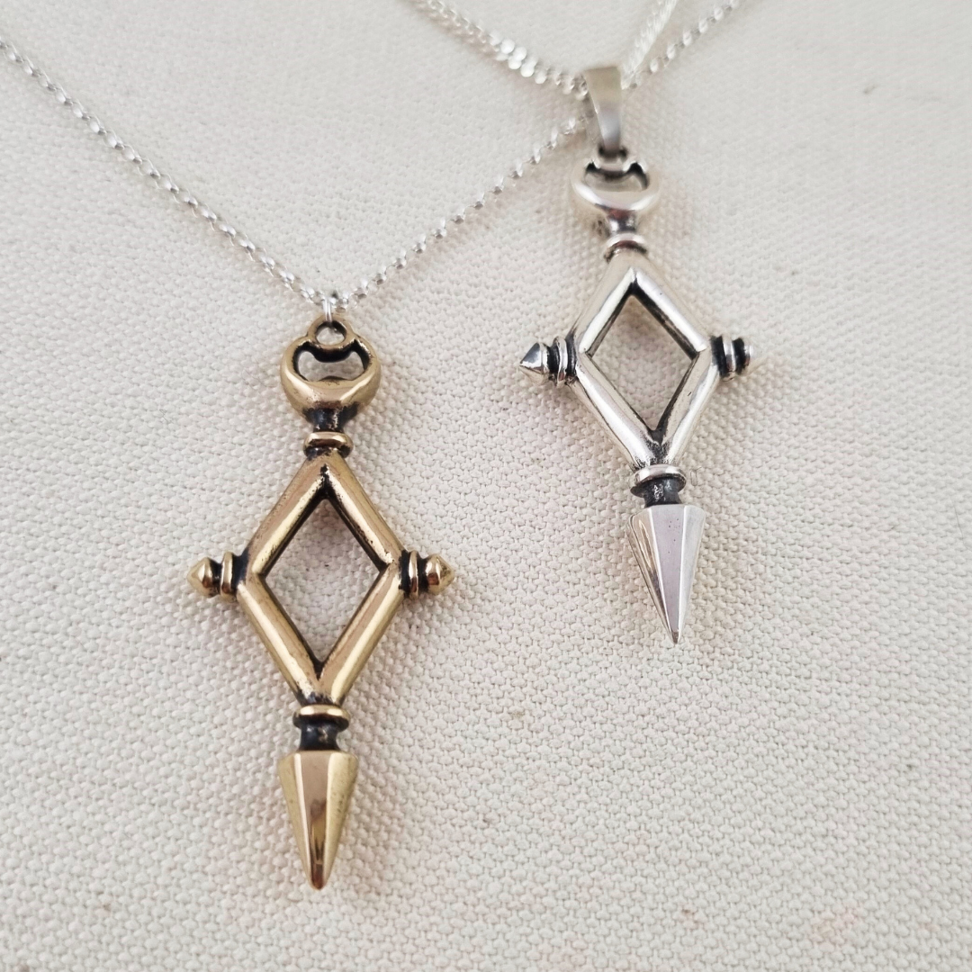 Two geometric pendants on necklaces against a neutral background