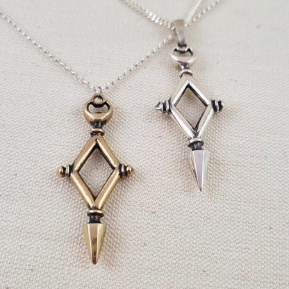 Two geometric pendants on necklaces against a neutral background