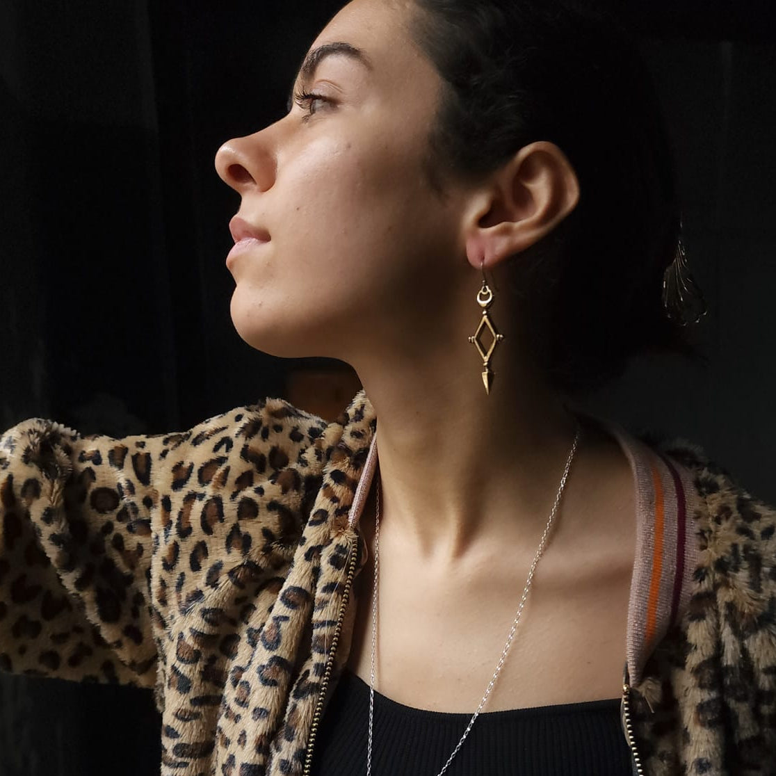 Woman wearing a leopard print jacket with gold jewelry against a dark background