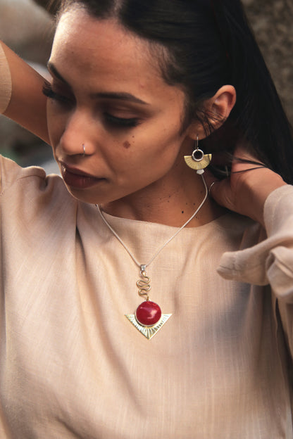 Woman wearing a necklace with a red pendant and gold accents