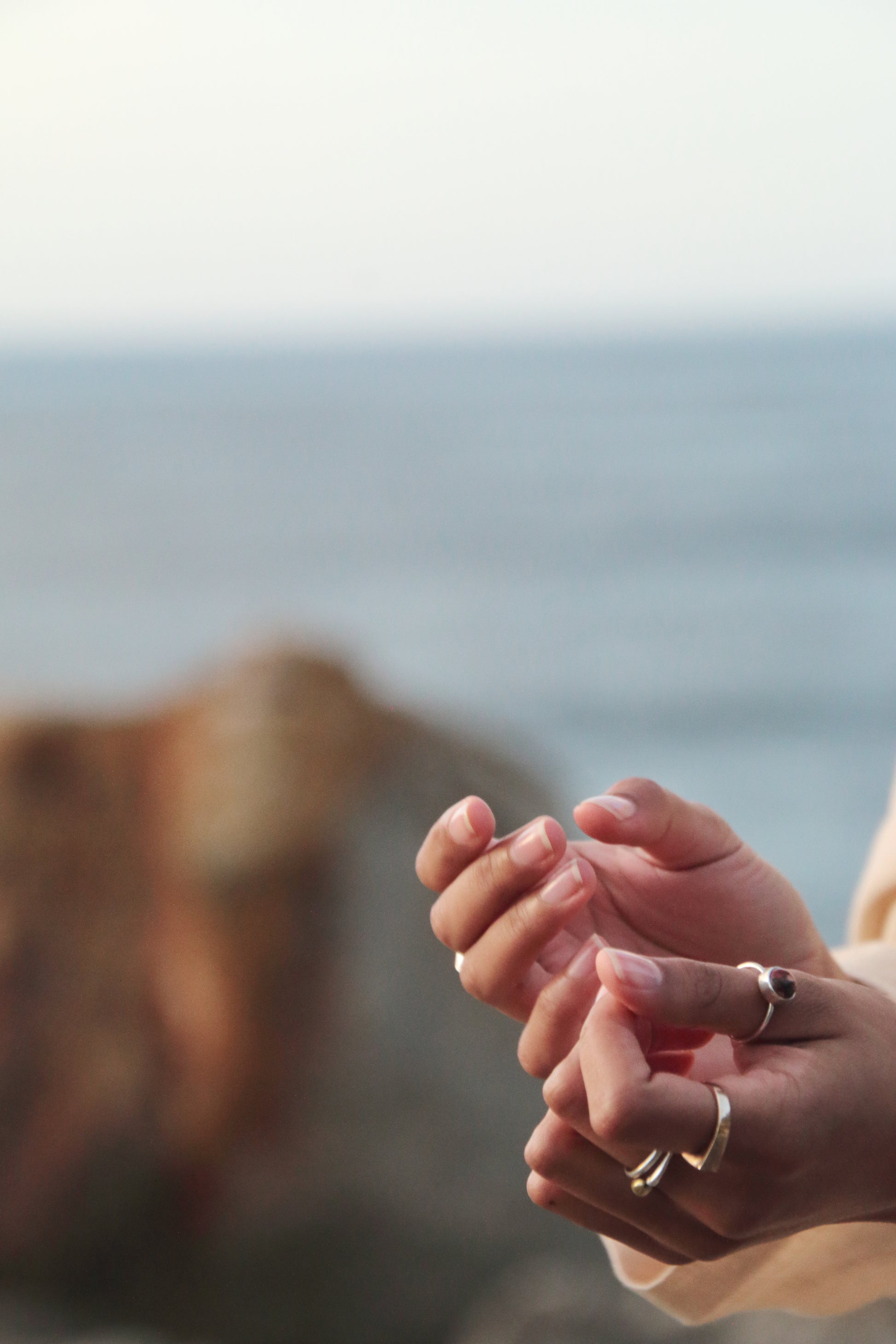 Close-up of hands with rings against a blurred natural background