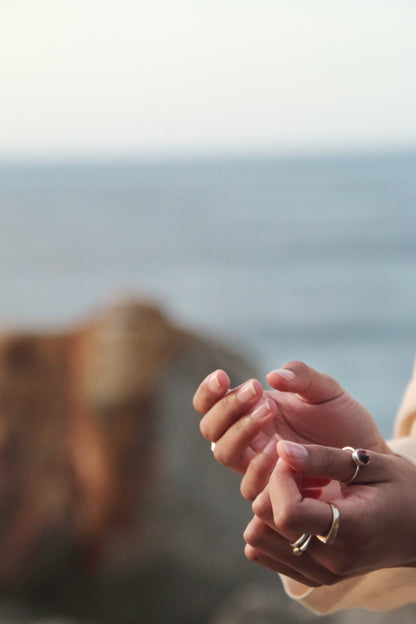 Close-up of hands with rings against a blurred natural background