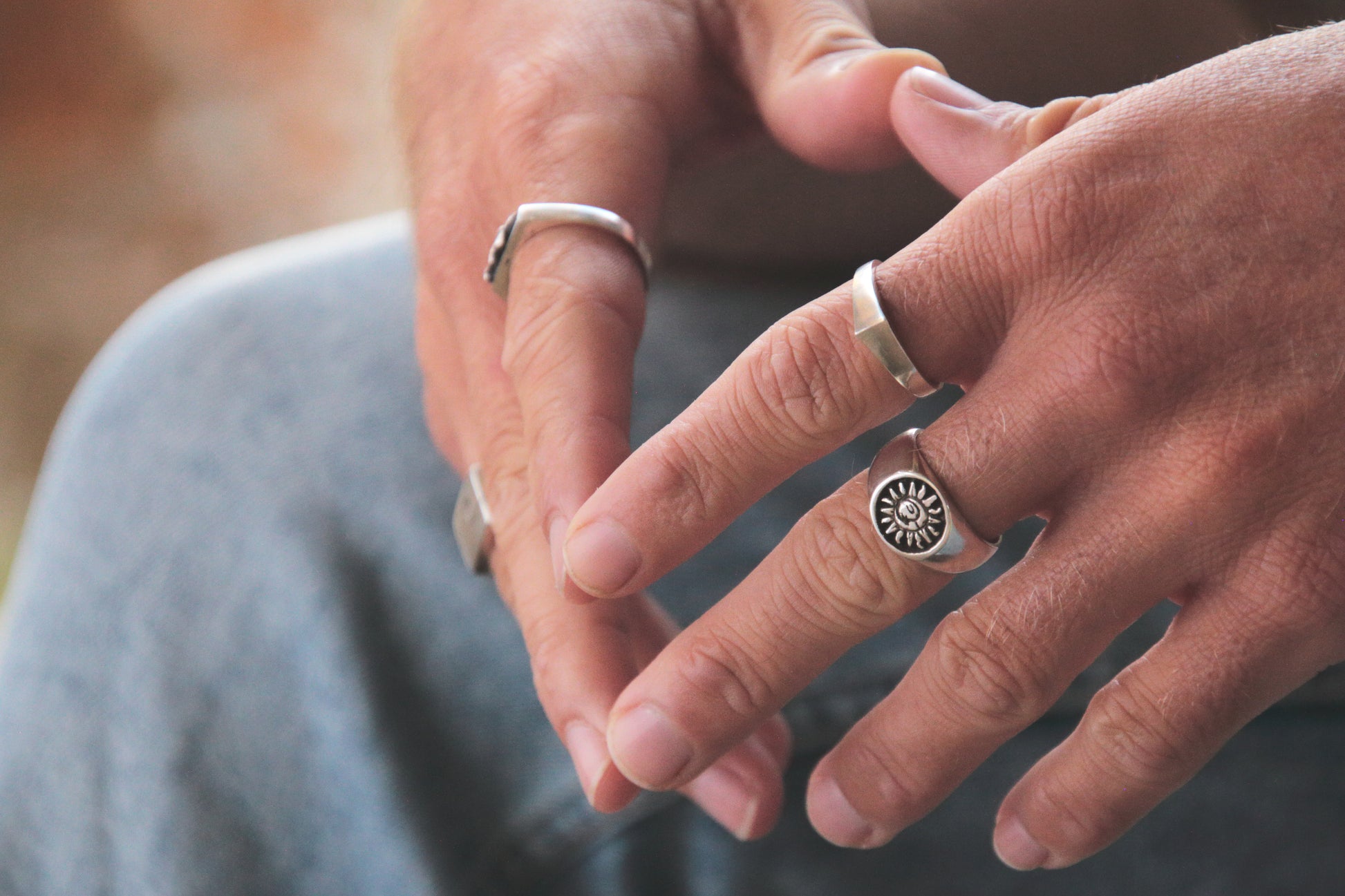 Close-up of two hands with silver rings on a blurred background