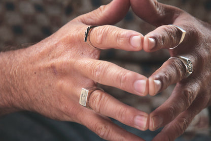 Close-up of two hands with rings making a heart shape.