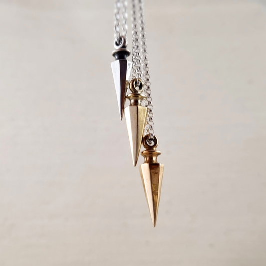 The Wayfinder Necklace collection in silver, brass and bronze, photographed on off-white background, earthy aesthetic.